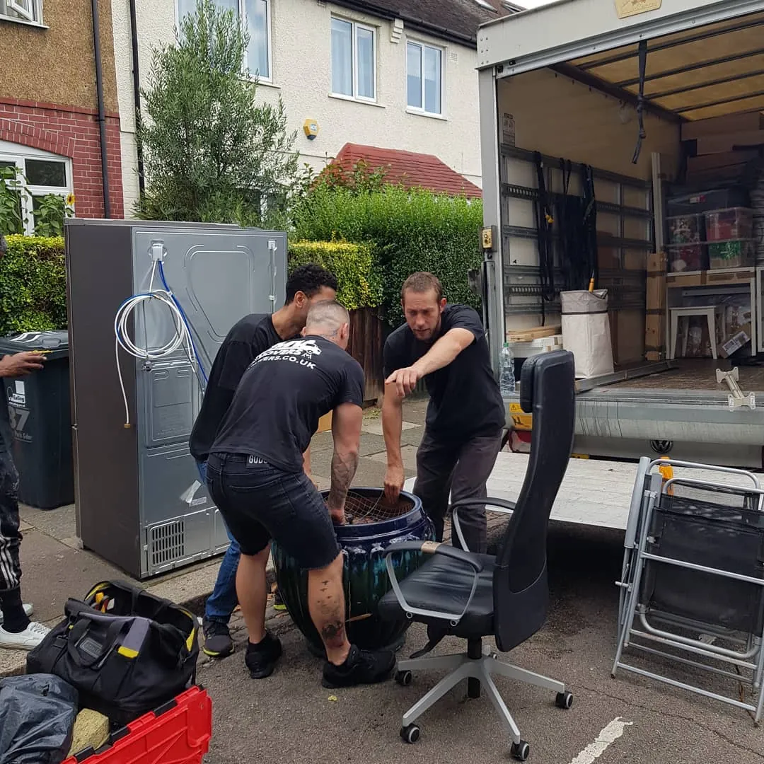 MV Movers crew loading office chairs and a fridge onto the van